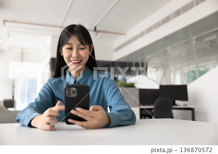 Joyful young Chinese professional woman typing on cell 136870572