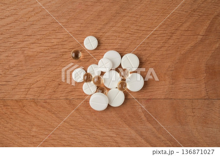 A bunch of various medicines, pills lying around without packaging on a wooden board 136871027