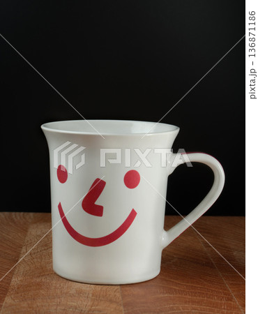 Mug with a smile pattern on a wooden board and black background 136871186