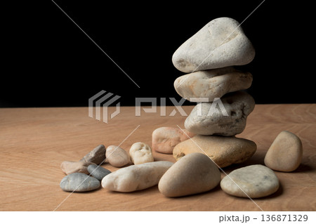 a bunch of smooth stones on a board on a black background 136871329