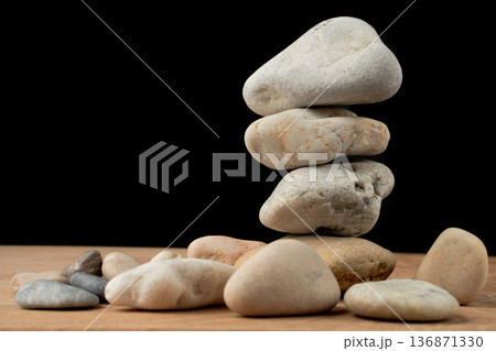 a bunch of smooth stones on a board on a black background a bunch of smooth stones on a board on a black background 136871330