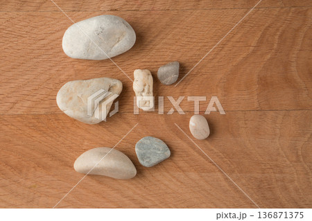 Smooth stones, of various sizes, are scattered on a wooden board Smooth stones, of various sizes, are scattered on a wooden board 136871375