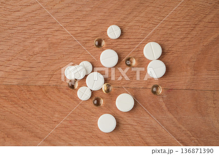 A bunch of various medicines, pills lying around without packaging on a wooden board 136871390