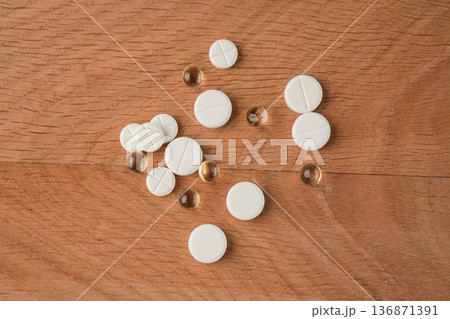A bunch of various medicines, pills lying around without packaging on a wooden board A bunch of various medicines, pills lying around without packaging on a wooden board 136871391