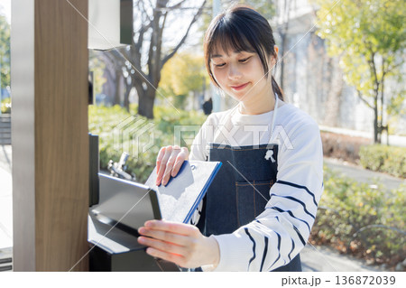回覧板を運ぶ女性 136872039