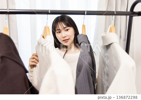 部屋で洋服を選ぶ女性 136872298