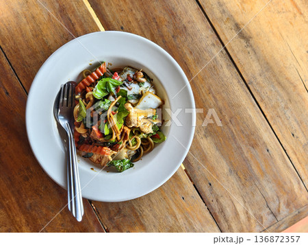 Spicy Thai drunken noodles spaghetti with vegetables on a wooden table. Spicy Thai drunken noodles spaghetti with vegetables on a wooden table. 136872357