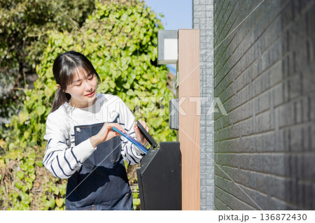 回覧板を運ぶ女性 136872430