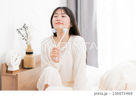 美顔器でマッサージするパジャマ姿の若いアジア人女性　 136872468