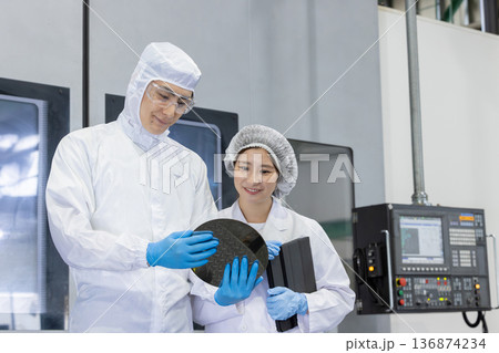 工場でタブレットPCを使う防護服を着た作業員 136874234