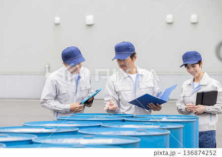 ドラム缶の在庫管理する作業員グループ 136874252