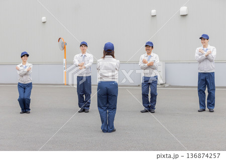 工場の前で体操する作業員グループ 136874257