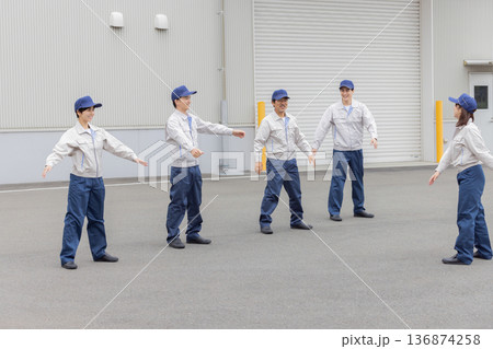 工場の前で体操する作業員グループ 136874258