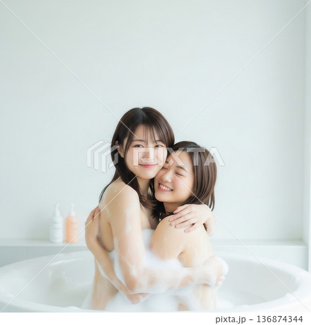 泡風呂に入ってお互いに抱きしめ合う二人の若い女性 136874344