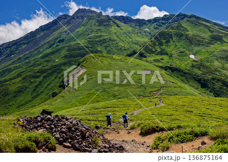 鳥海山・御田ヶ原付近を行く登山者と新山山頂 136875164