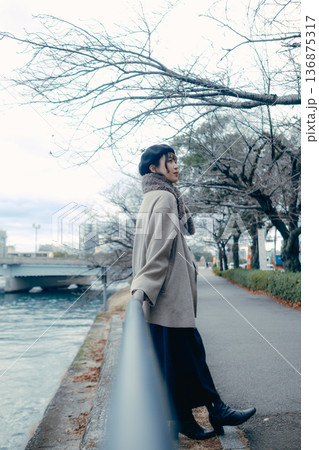 冬の川沿いで空を見上げる30代日本人女性 136875317