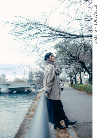 冬の川沿いで空を見上げる30代日本人女性 136875318