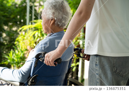 Caregiver help and care Asian senior woman patient sitting on wheelchair in park. 136875351