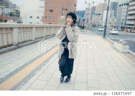 冬の都会を歩く笑顔の30代日本人女性 冬の都会を歩く笑顔の30代日本人女性 136875497