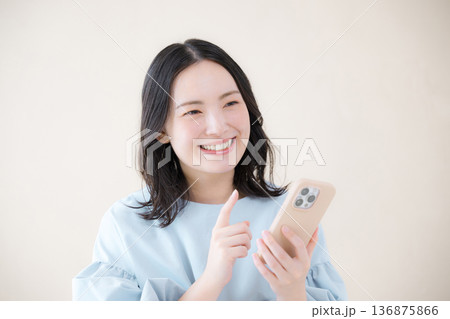 スマホを操作する笑顔の女性 オンライン利用・サービスなどの口コミや申し込みをするイメージ スマホを操作する笑顔の女性 オンライン利用・サービスなどの口コミや申し込みをするイメージ 136875866
