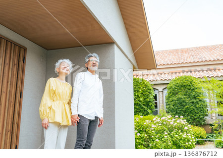 笑顔で住宅の前に立つシニアカップル 笑顔で住宅の前に立つシニアカップル 136876712