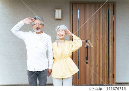 笑顔で住宅の前に立つシニアカップル 136876716