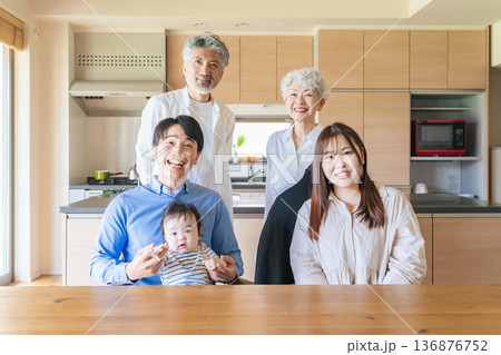 笑顔で赤ちゃんを囲む三世代家族 笑顔で赤ちゃんを囲む三世代家族 136876752