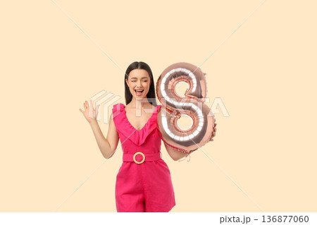 A young woman joyfully holds a balloon while celebrating 136877060