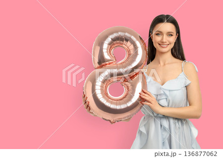 Woman smiles with a big balloon shaped like an 8 Woman smiles with a big balloon shaped like an 8 136877062