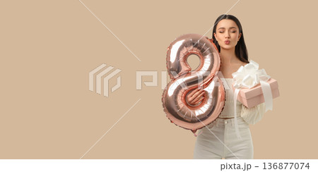 A woman celebrates with a gift and a balloon 136877074