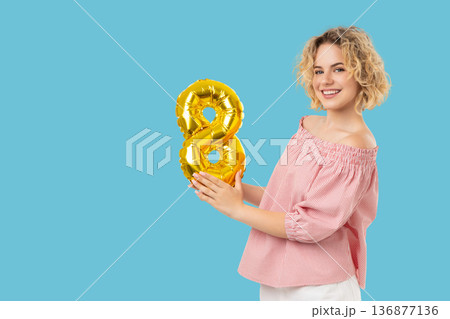 A girl holds a golden balloon shaped like number eight A girl holds a golden balloon shaped like number eight 136877136