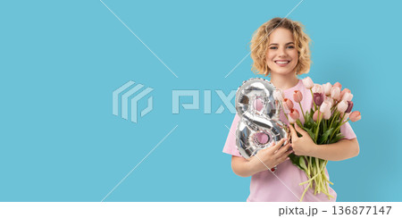 A woman holds flowers and a balloon while smiling A woman holds flowers and a balloon while smiling 136877147