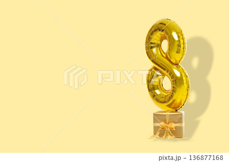 A gold number 8 balloon sits next to a gift A gold number 8 balloon sits next to a gift 136877168
