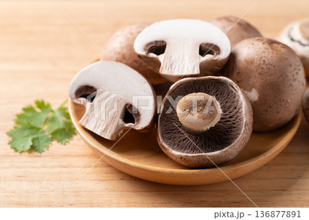 Fresh crimini mushroom or baby bella mushroom on wooden plate prepared for cooking Fresh crimini mushroom or baby bella mushroom on wooden plate prepared for cooking 136877891