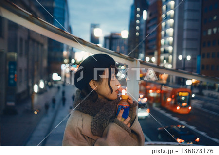 夜の都会で温かい飲み物を持つ30代日本人女性 136878176
