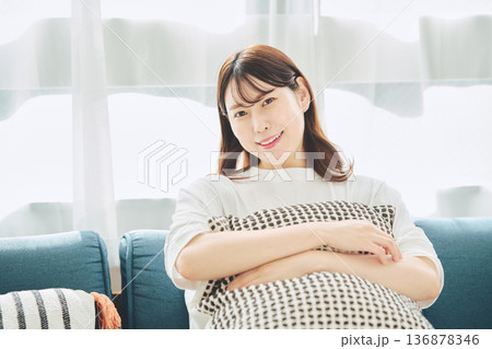 自然光のリビングでリラックスして微笑む30代女性のポートレート 136878346