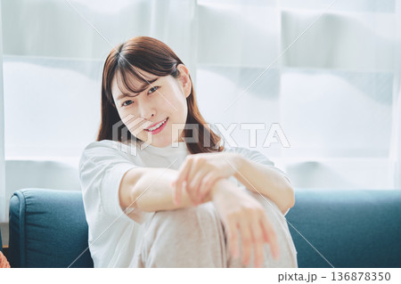 自然光のリビングでリラックスして微笑む30代女性のポートレート 自然光のリビングでリラックスして微笑む30代女性のポートレート 136878350
