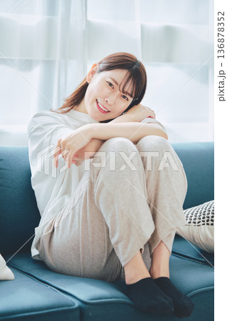 自然光のリビングでリラックスして微笑む30代女性のポートレート 136878352