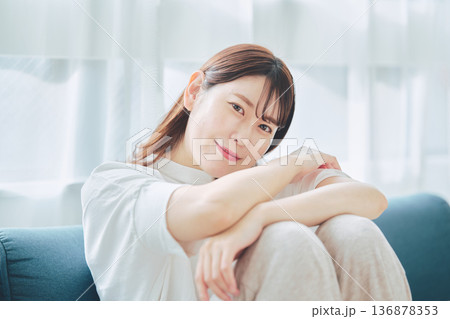 自然光のリビングでリラックスして微笑む30代女性のポートレート 自然光のリビングでリラックスして微笑む30代女性のポートレート 136878353