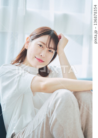自然光のリビングでリラックスして微笑む30代女性のポートレート 自然光のリビングでリラックスして微笑む30代女性のポートレート 136878354
