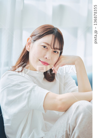 自然光のリビングでリラックスして微笑む30代女性のポートレート 136878355