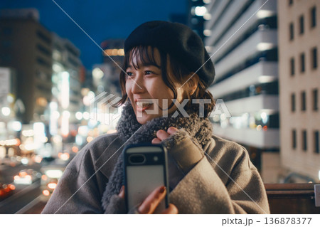 夜の都会でスマートフォンを使う笑顔の日本人女性 136878377