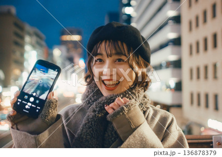 夜の都会でスマートフォンを使う笑顔の日本人女性 夜の都会でスマートフォンを使う笑顔の日本人女性 136878379