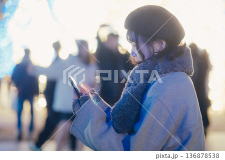 イルミネーションの前でスマートフォンを見る女性 イルミネーションの前でスマートフォンを見る女性 136878538