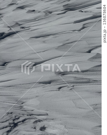 Wind-sculpted snow drifts and textured snow surface on a cold winter slope Wind-sculpted snow drifts and textured snow surface on a cold winter slope 136878684