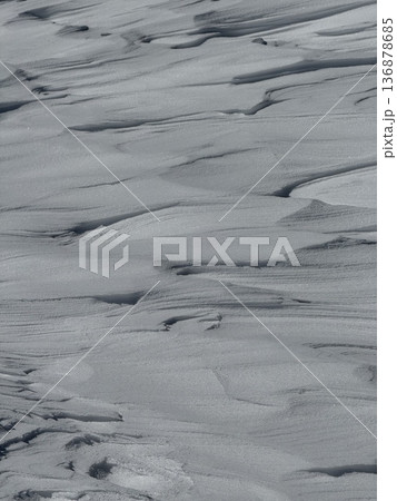 Wind-sculpted snowdrifts and textured winter snow surface with soft ripples and shadows 136878685