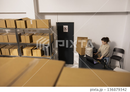 Team of dispatch workers managing shipment quality control, managing packages and supporting e-business in house operations with accurate delivery logistics. Product handling in small depot. Team of dispatch workers managing shipment quality control, managing packages and supporting e-business in house operations with accurate delivery logistics. Product handling in small depot. 136879342