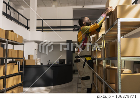 Small business worker preparing parcels in a storage depot, handling inventory for e-shop shipments and ensuring product quality control. Support online shopping and express delivery. 136879771