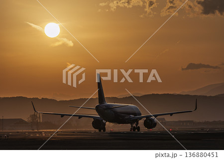 夕暮れの仙台空港　夕日と離陸中の飛行機　宮城県名取市 136880451