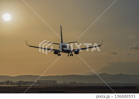 夕暮れの仙台空港　夕日と着陸中の飛行機　宮城県名取市 136880555